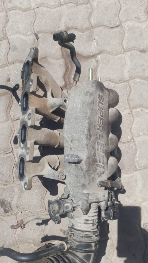 Front angled view of a Kia Shuma 2 1.6 intake manifold displayed against a plain background.Front angled view