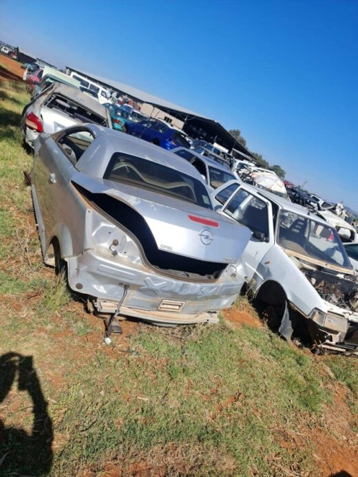 Front and side view of a stripped silver hatchback car with missing parts, showing body shell and wheels.Front
