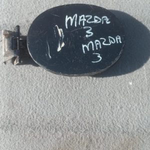 Used fuel flap for Mazda 3, shown from the outer side with mounting points visible, slightly angled.Used fuel